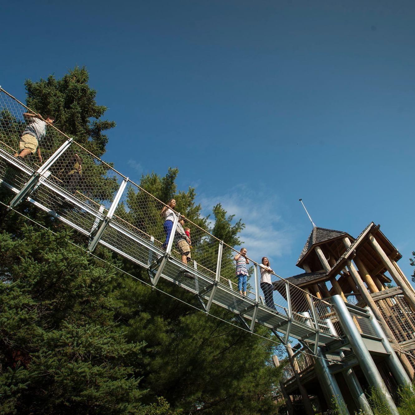 People on a metal bridge at the Wild Center, High Peaks Resort
