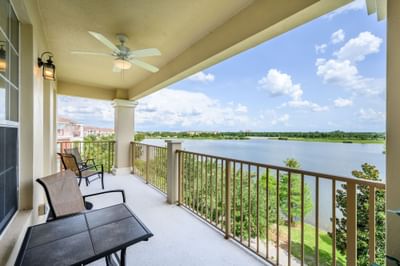 Balcony with lake view, table, chairs, ceiling fan, and railing at Vista Cay Resort By Millenium