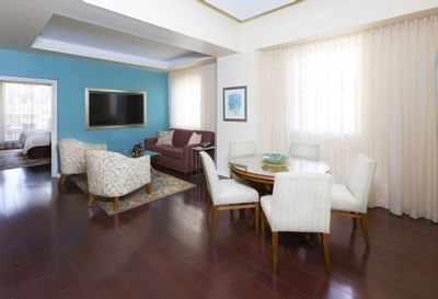 Imperial Penthouse with modern living room with dining set, couch, TV, and art, adjacent to a bedroom with a bed.