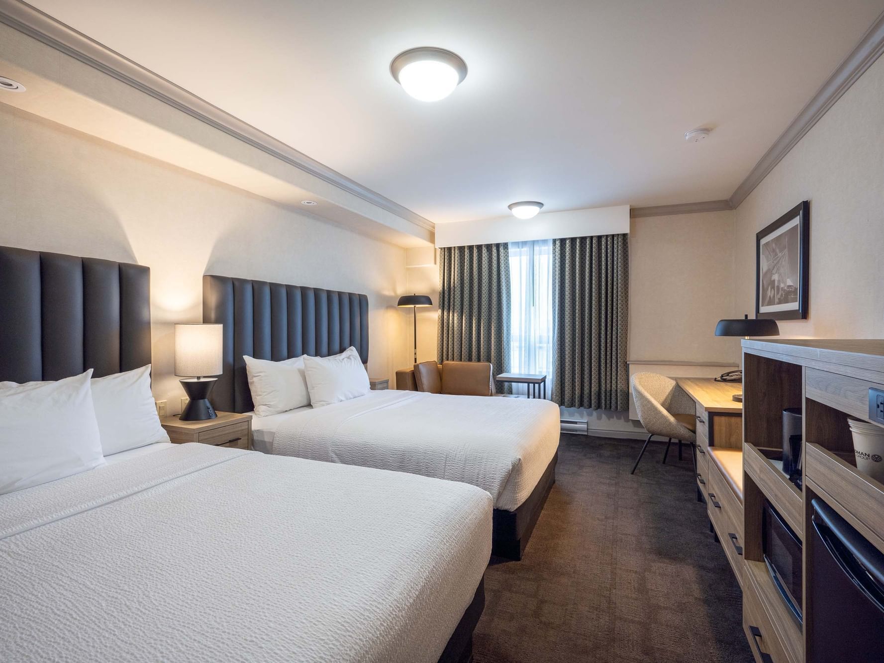 Two beds with nightstands and
workspace in Standard Room at Sandman Hotel & Suites Winnipeg Airport