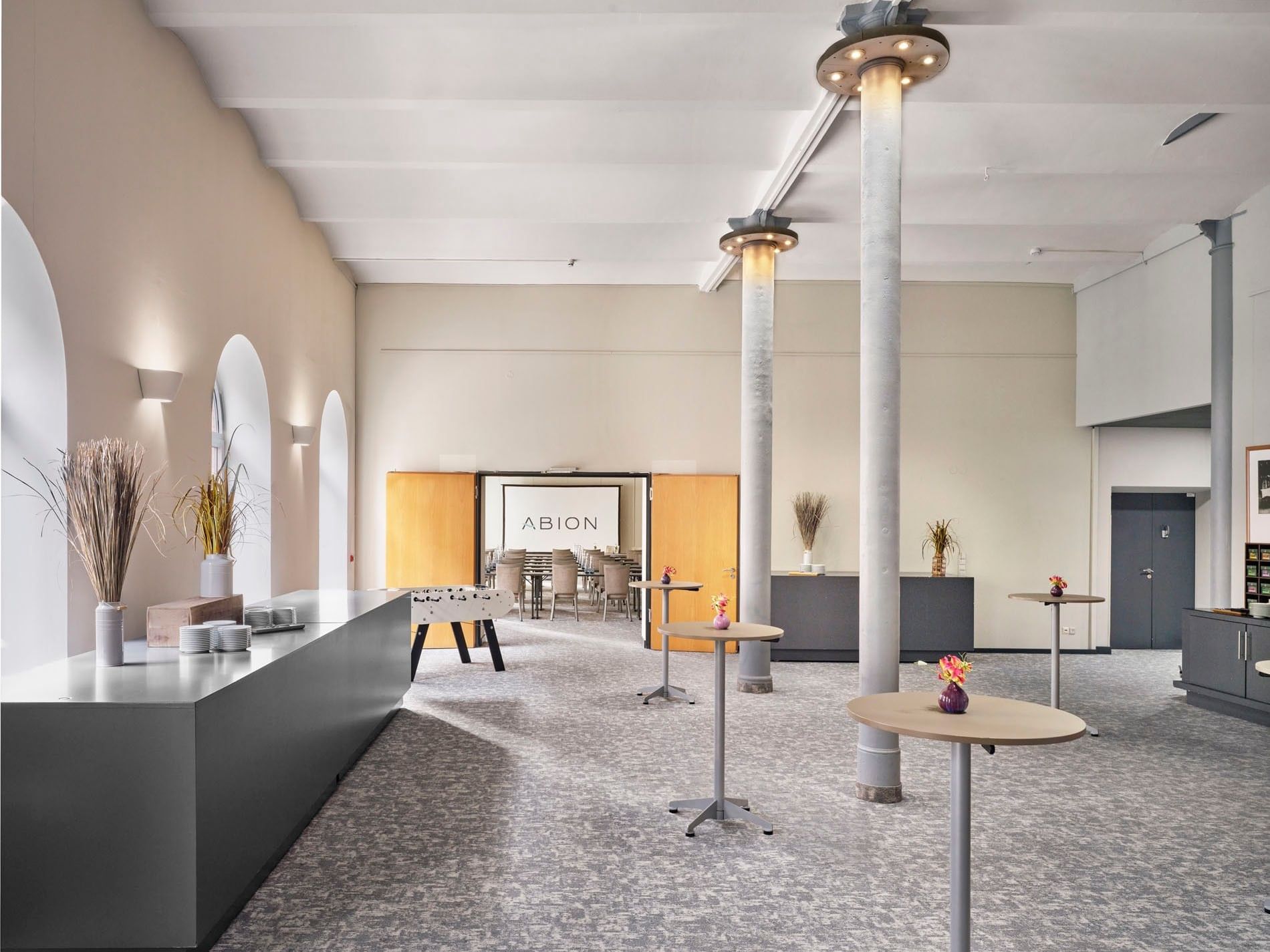 Elegantly furnished lounge area with round tables and floral decorations at Abion Spreebogen Waterside Hotel Berlin.