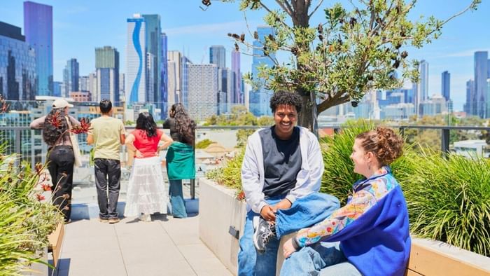 People enjoying the rooftop garden with a cityscape view at UniLodge Royal Melbourne in North Melbourne.