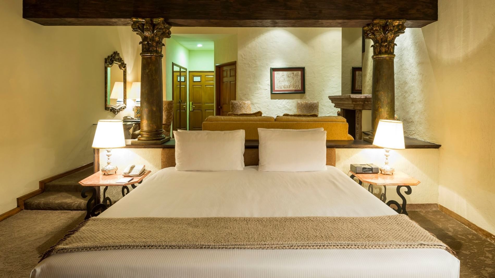 King Grand Class luxury bed framed by stone columns and a large mirror at Quinta Real Aguascalientes
