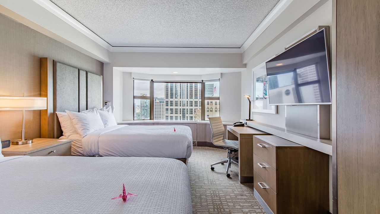 Accessible hotel guestroom with two beds, TV, and desk