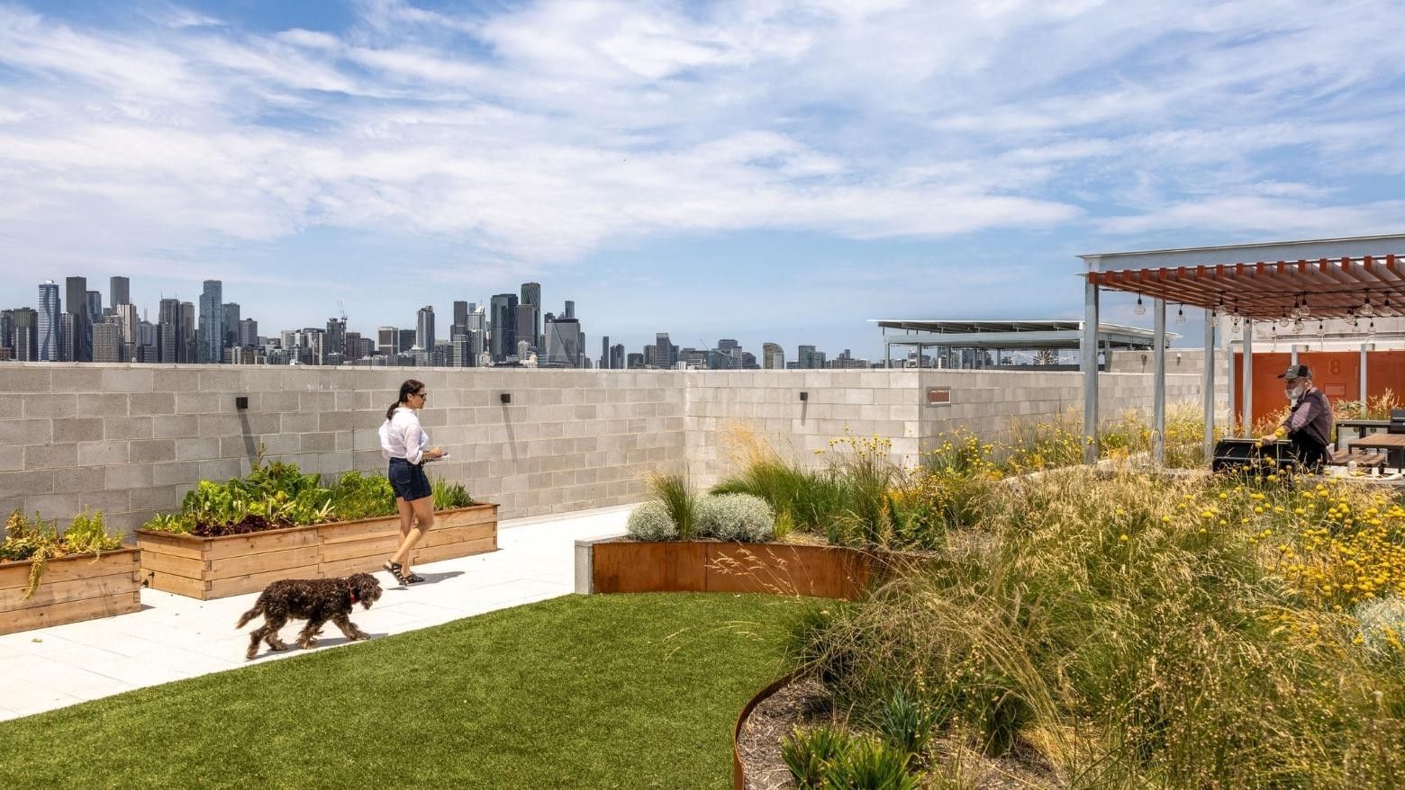 Woman jogging with dog on rooftop terrace featuring green lawn, planters, and city skyline views during Swift Walk.