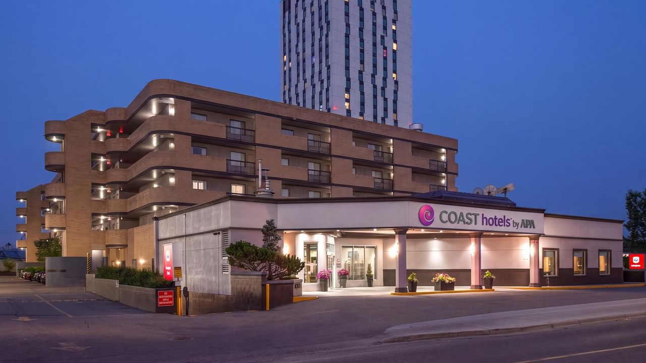 Illuminated exterior view of a modern multi-story hotel building at dusk with prominent entrance and signage