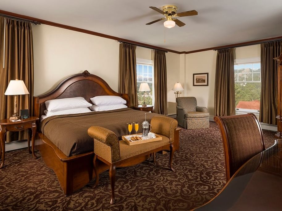 Elegant room at Stanley Hotel with large bed, armchairs, and a breakfast tray.