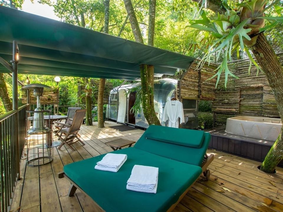 Zona de descanso al aire libre con un tráiler Airstream, una bañera de hidromasaje y dos tumbonas verdes, Casa Santo Domingo