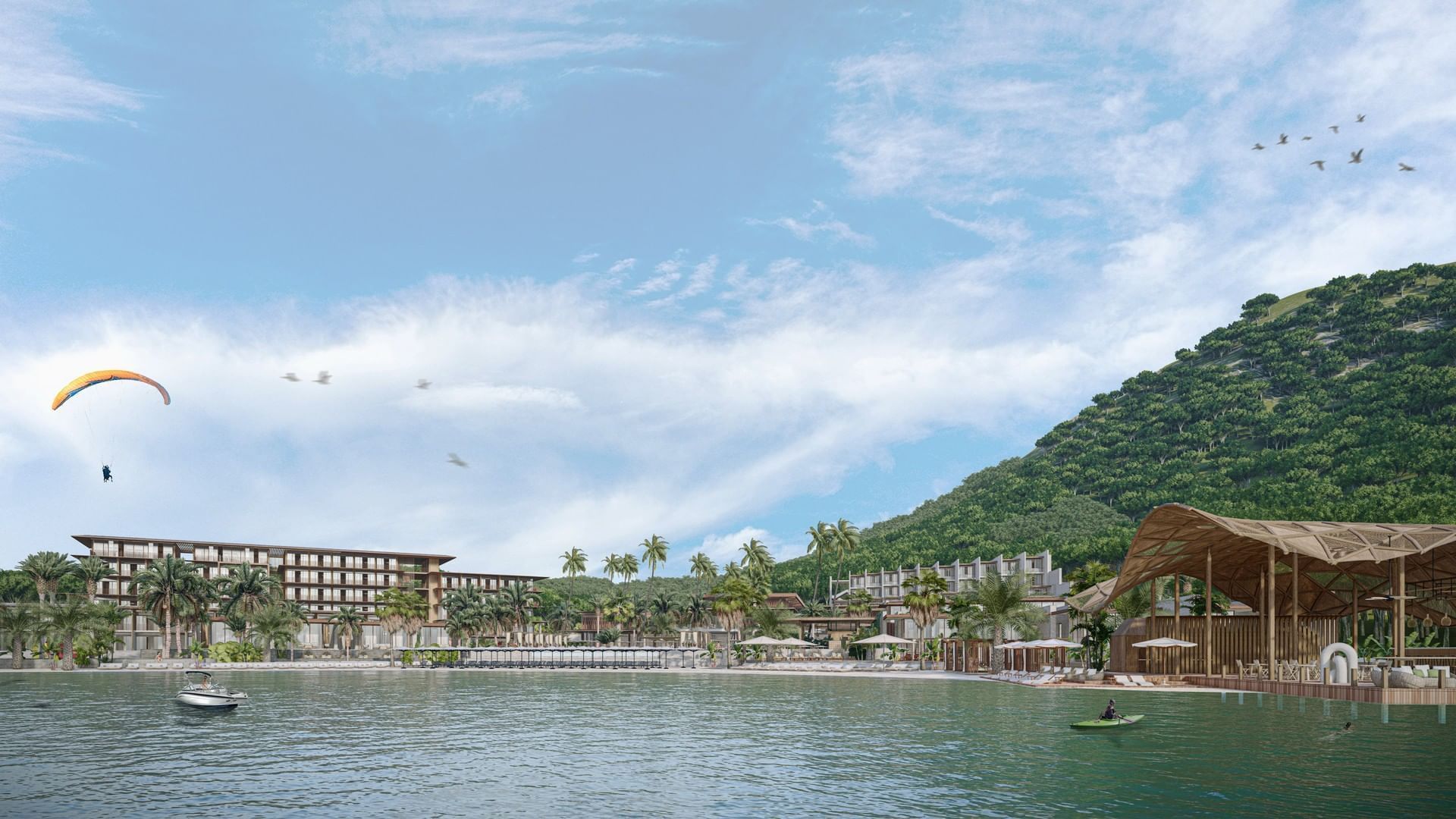 Paraglider soaring over A'ila Resorts, with a vibrant beachfront, a lush hill, and a clear blue sky