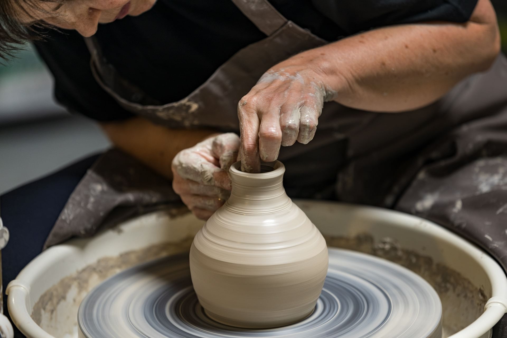 Woman making vase on pottery wheel