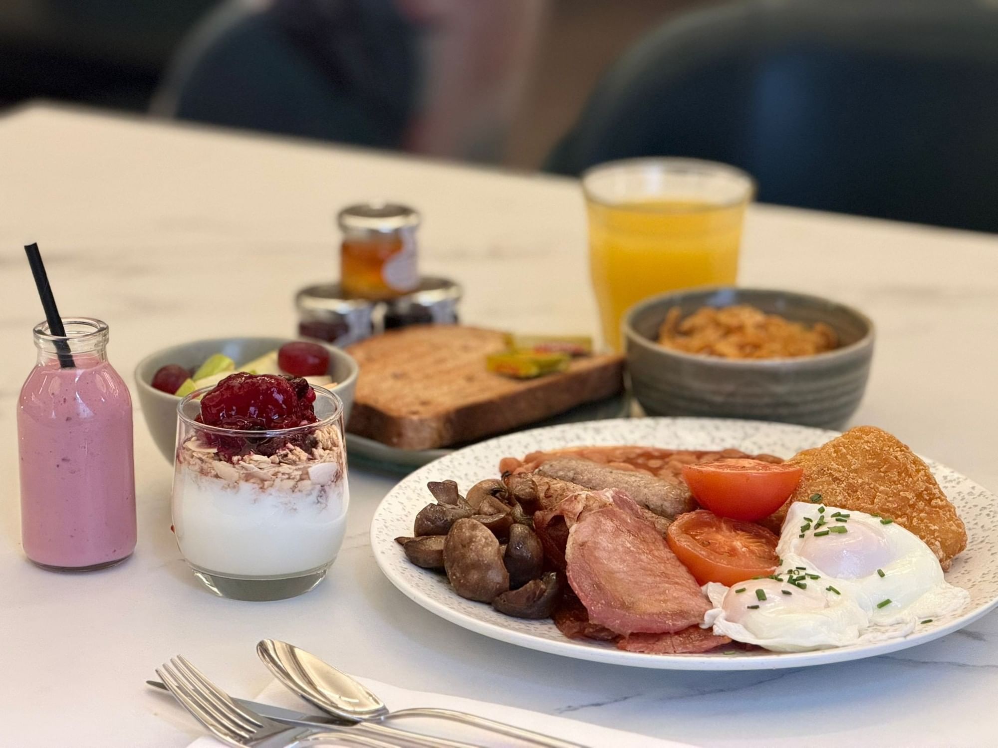 Full English breakfast plate served with a berry yogurt parfait and a smoothie at The Met Hotel Leeds, England