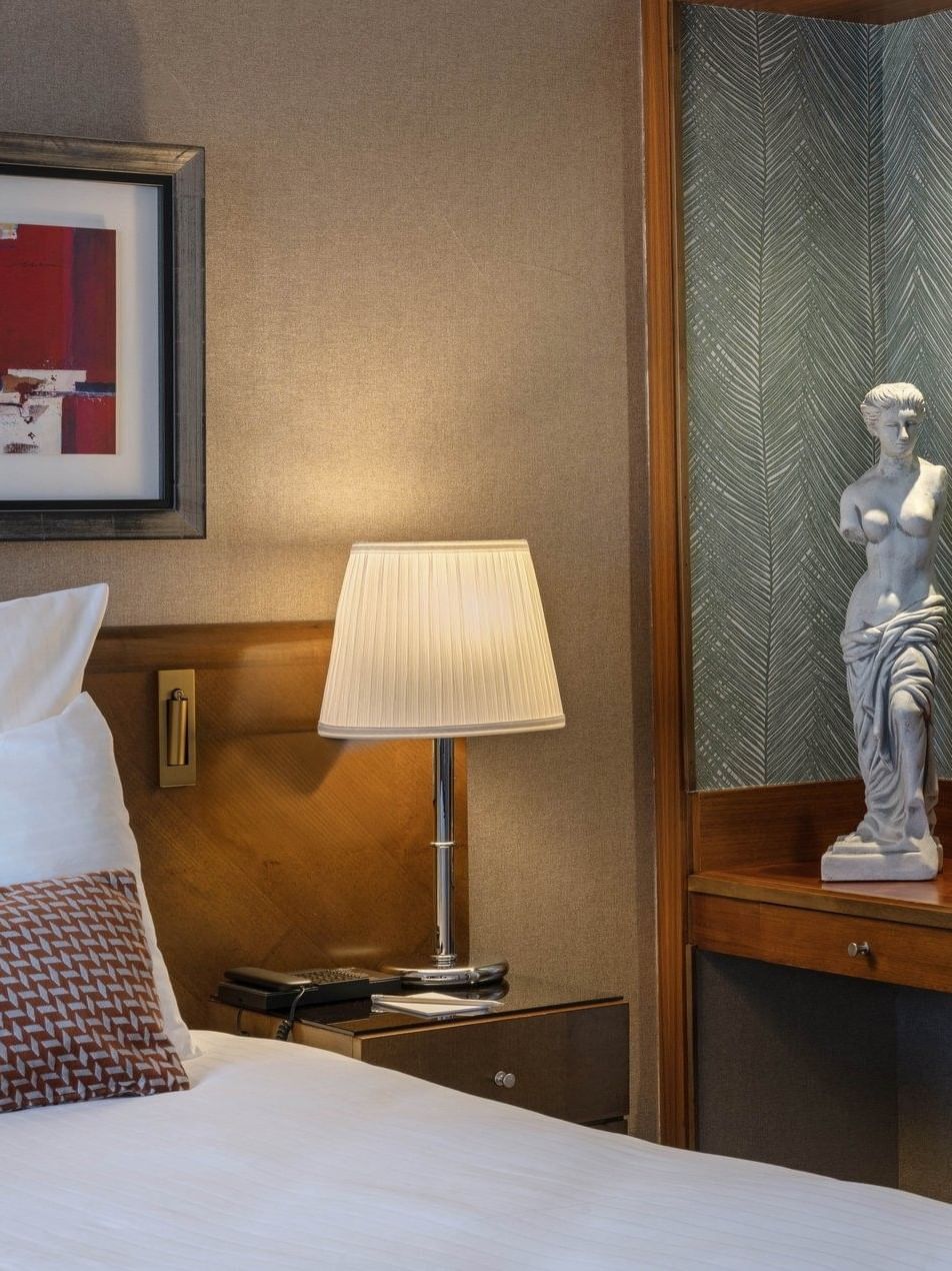 Warwick Suite with a lamp placed by a statue on a wooden stand at Warwick Grand Place Brussels