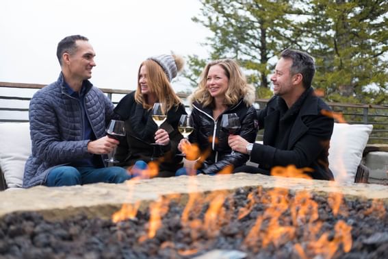 Four people toasting with wine near Terrace Fire Pit in The 7880 Club at Stein Eriksen Residences