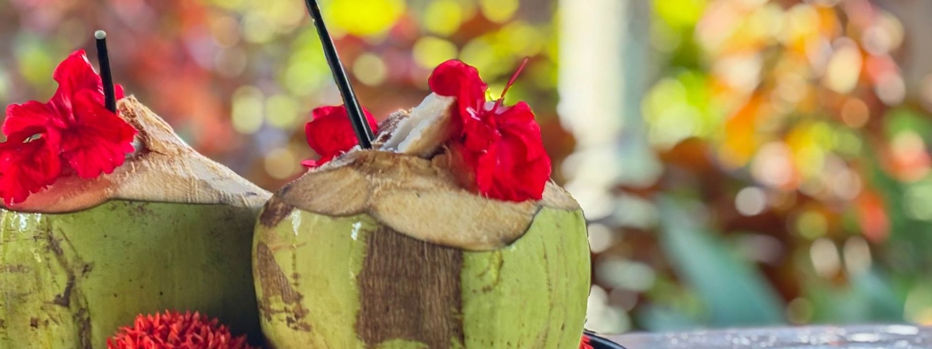 Two coconut drinks with straws and red flowers on a plate at The Naviti Resort in Korolevu