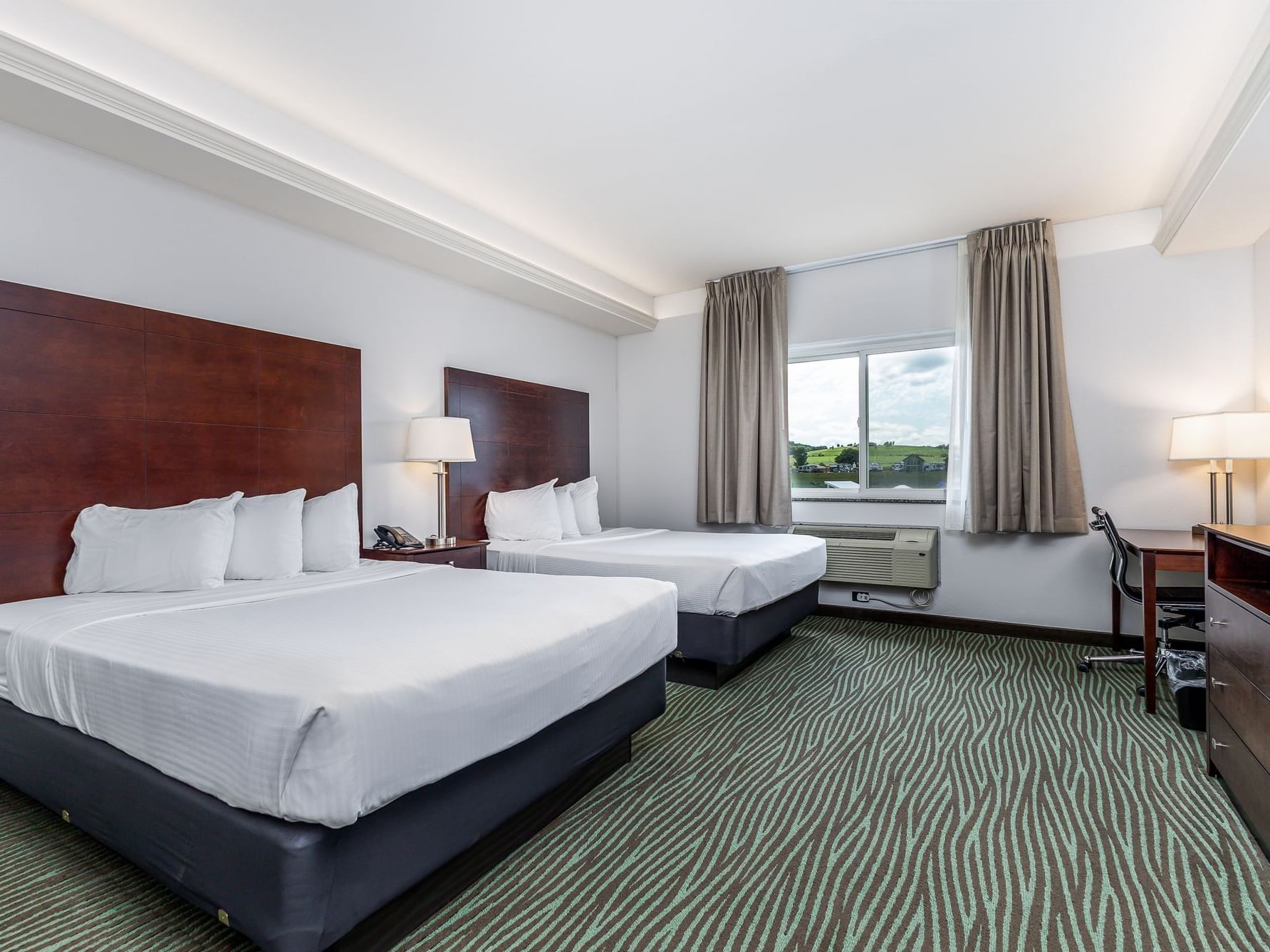 Nightstand and work desk by the cozy beds in Queen Resort View Room with patterned carpet at Off Shore Resort
