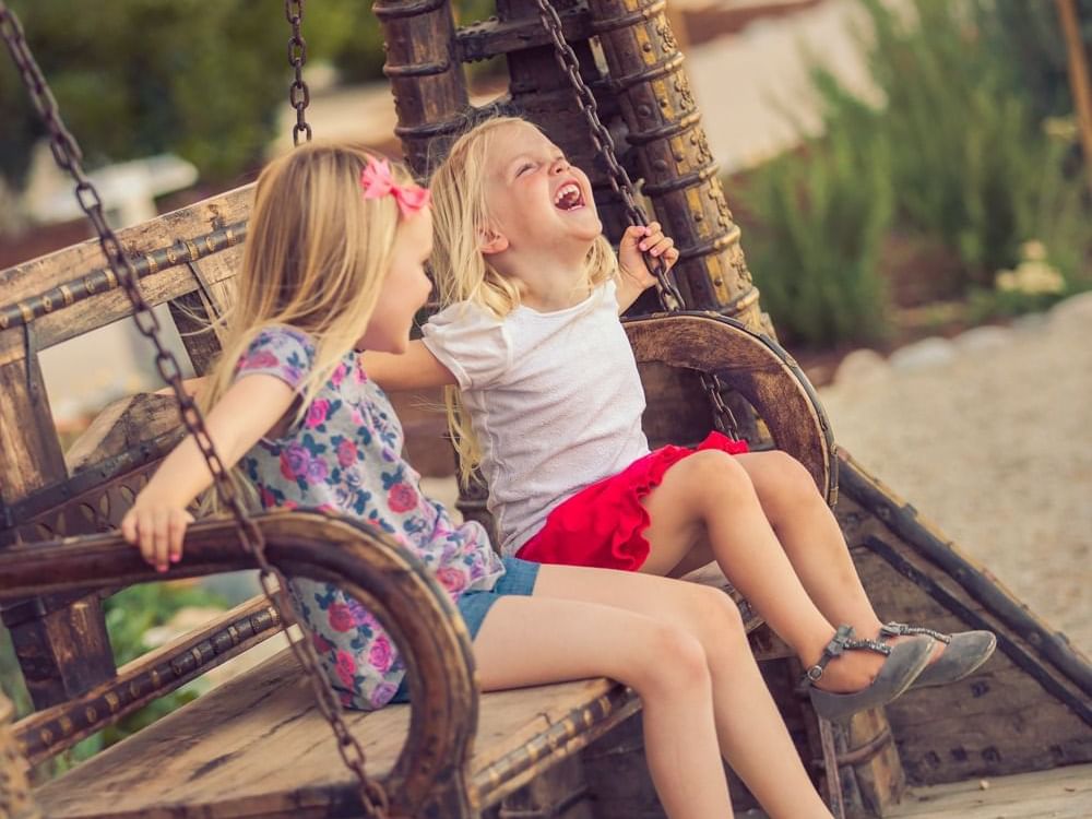 Two children sitting on a swing in courtyard