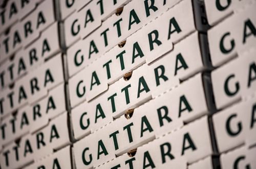 Stacked white pizza boxes with dark green Gattara branding by a storage wall in Gattara Restaurant & Patio at Warwick Denver