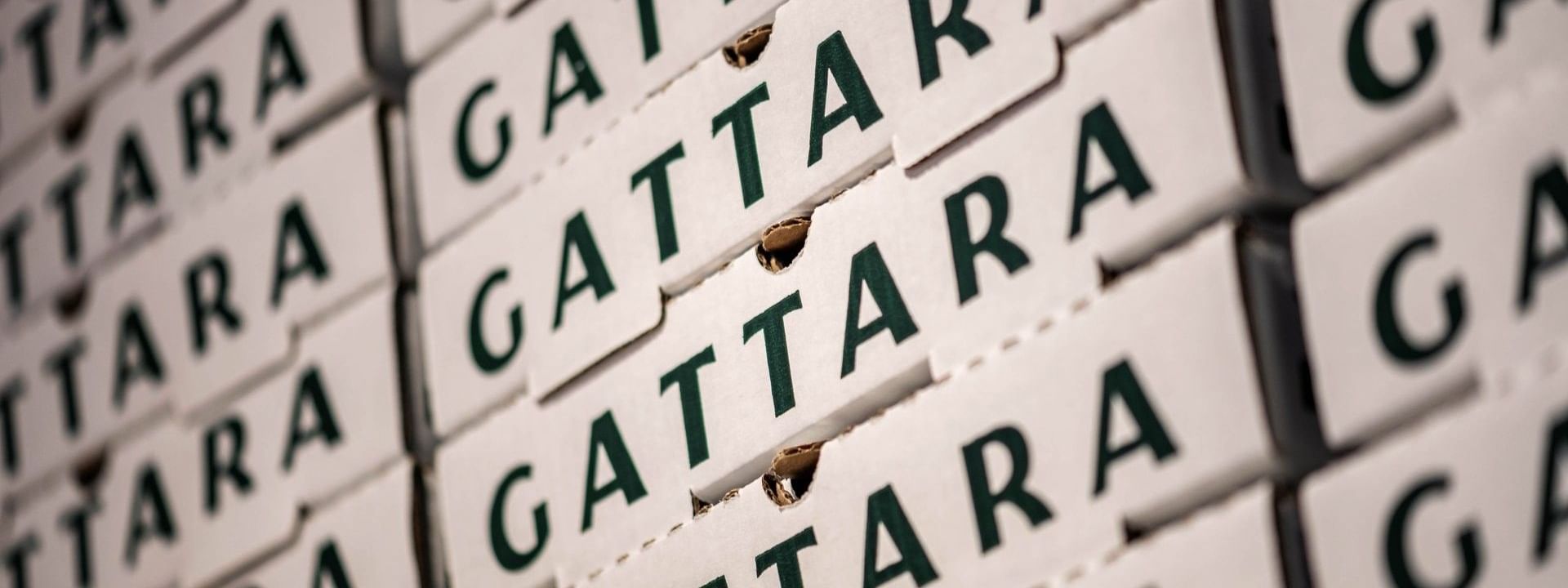 Stacked white pizza boxes with dark green Gattara branding by a storage wall in Gattara Restaurant & Patio at Warwick Denver