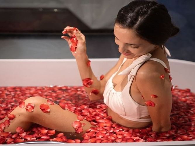 A lady in a bathtub with red rose flowers at Chatrium Grand Bangkok