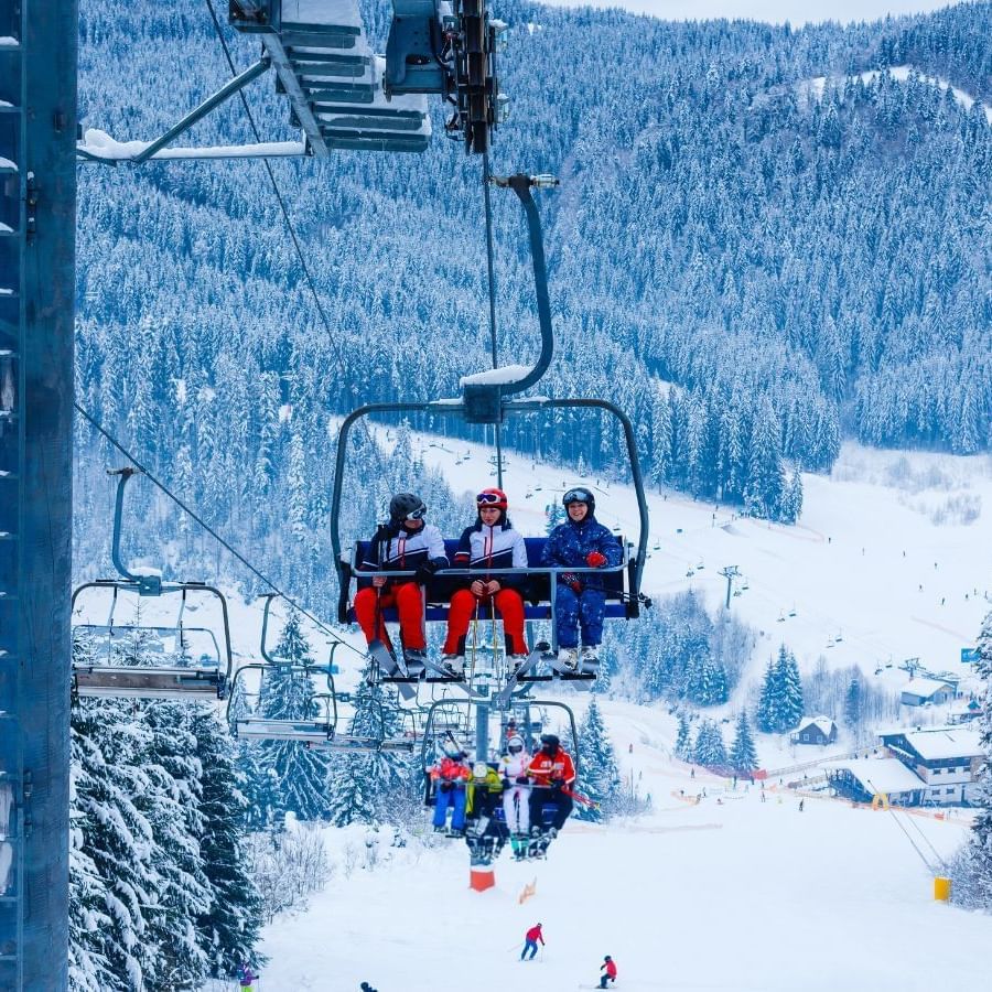 Group of people riding ski lift with snowy mountain backdrop near Blackcomb Springs Suites