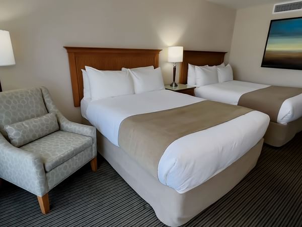 Guest room with two queen beds, chair, and lamps