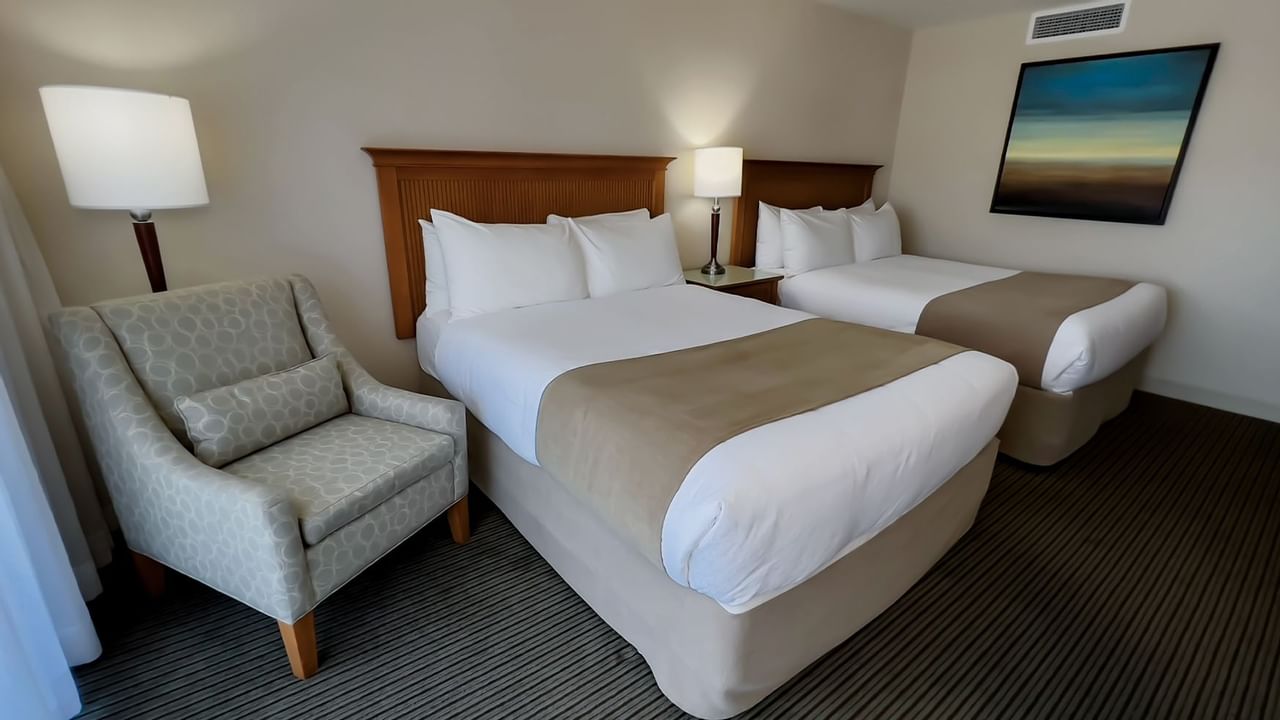 Guest room with two queen beds, chair, and lamps