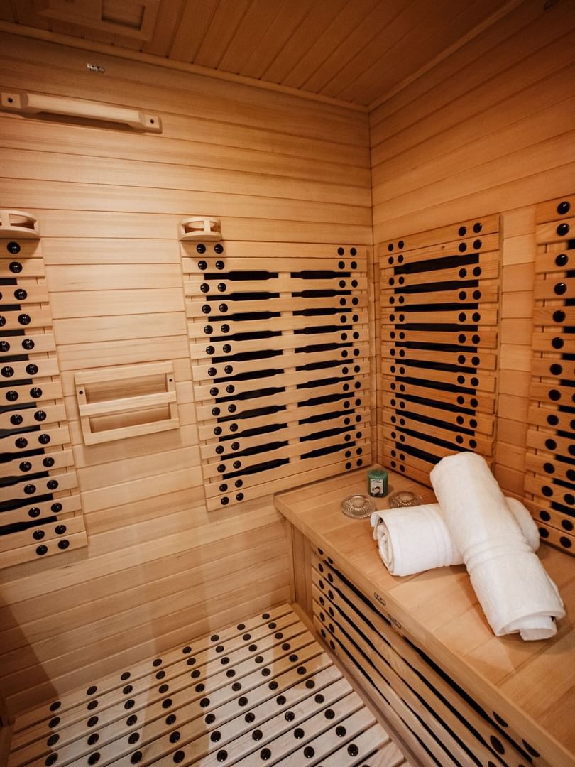 White towels on a wooden bench by a sauna wall featuring black infrared heaters at Cantonal Hotel by Warwick Riyadh