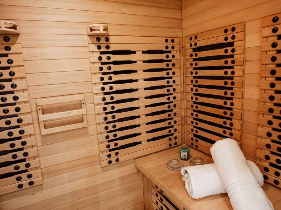 White towels on a wooden bench by a sauna wall featuring black infrared heaters at Cantonal Hotel by Warwick Riyadh