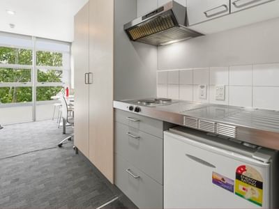 Modern kitchen area with appliances and large windows at Student Living Auckland - Beach.
