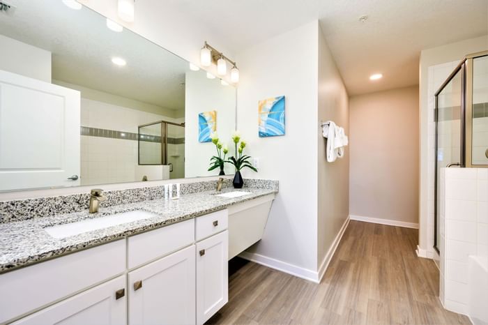 ADA room with modern bathroom with large mirror, two sinks, and a walk-in shower at Vista Cay Resort By Millenium