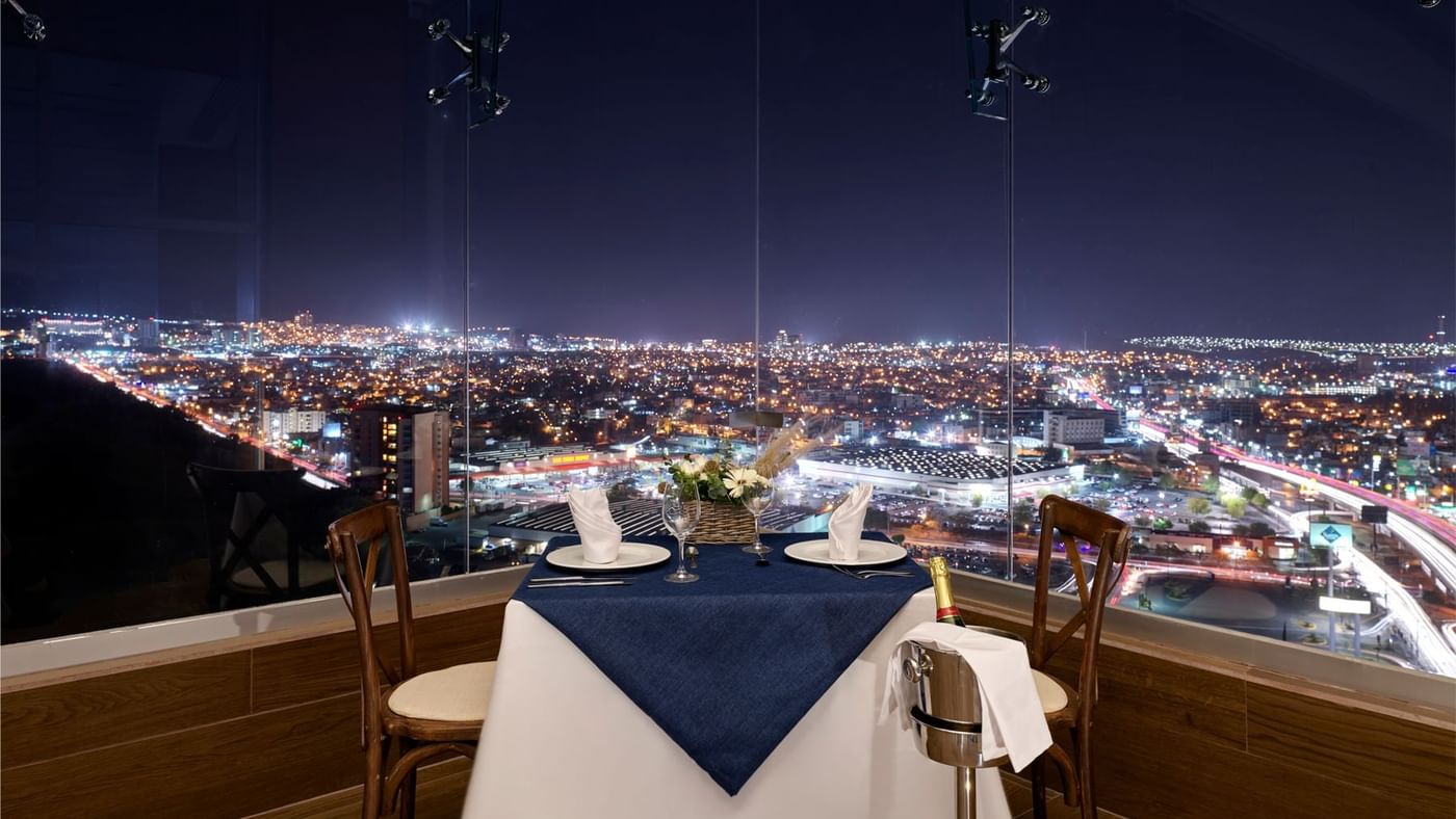 Mesa de comedor privada con vista nocturna a la ciudad en FA Hotels & Resorts