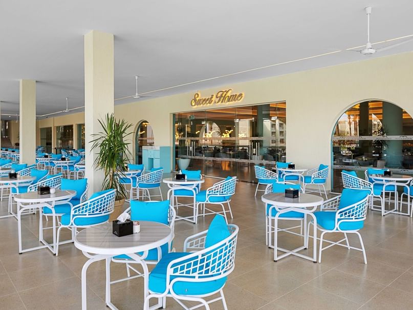 Sweet Home restaurant with white tables and bright blue chairs under a covered terrace at Pickalbatros White Beach Resort.