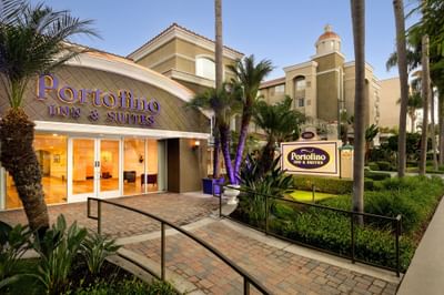Exterior of Anaheim Portofino Inn with benches by green hedges featuring hotel in Anaheim with shuttle to Disneyland resort