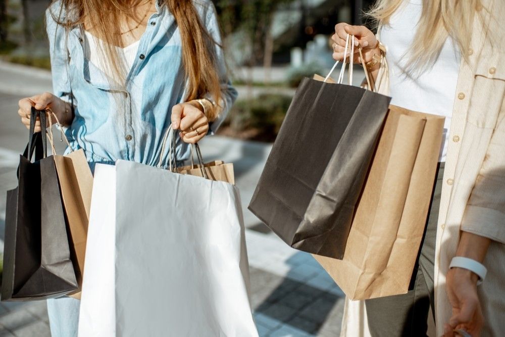The torsos of two women carrying shopping bags while shopping in Orlando.