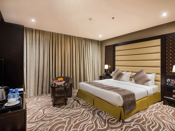 King Deluxe with a bed, carpeted floor, and an armchair at Warwick Al Khobar