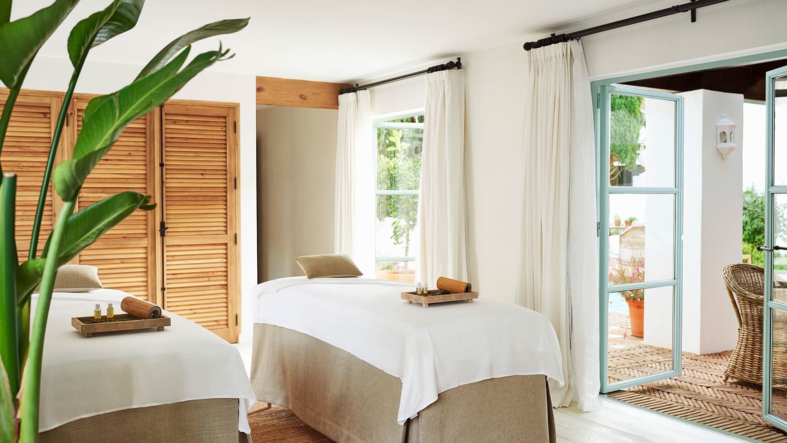 Spa with two massage tables by a window and a blue glass door opening to a patio at the Marbella Club