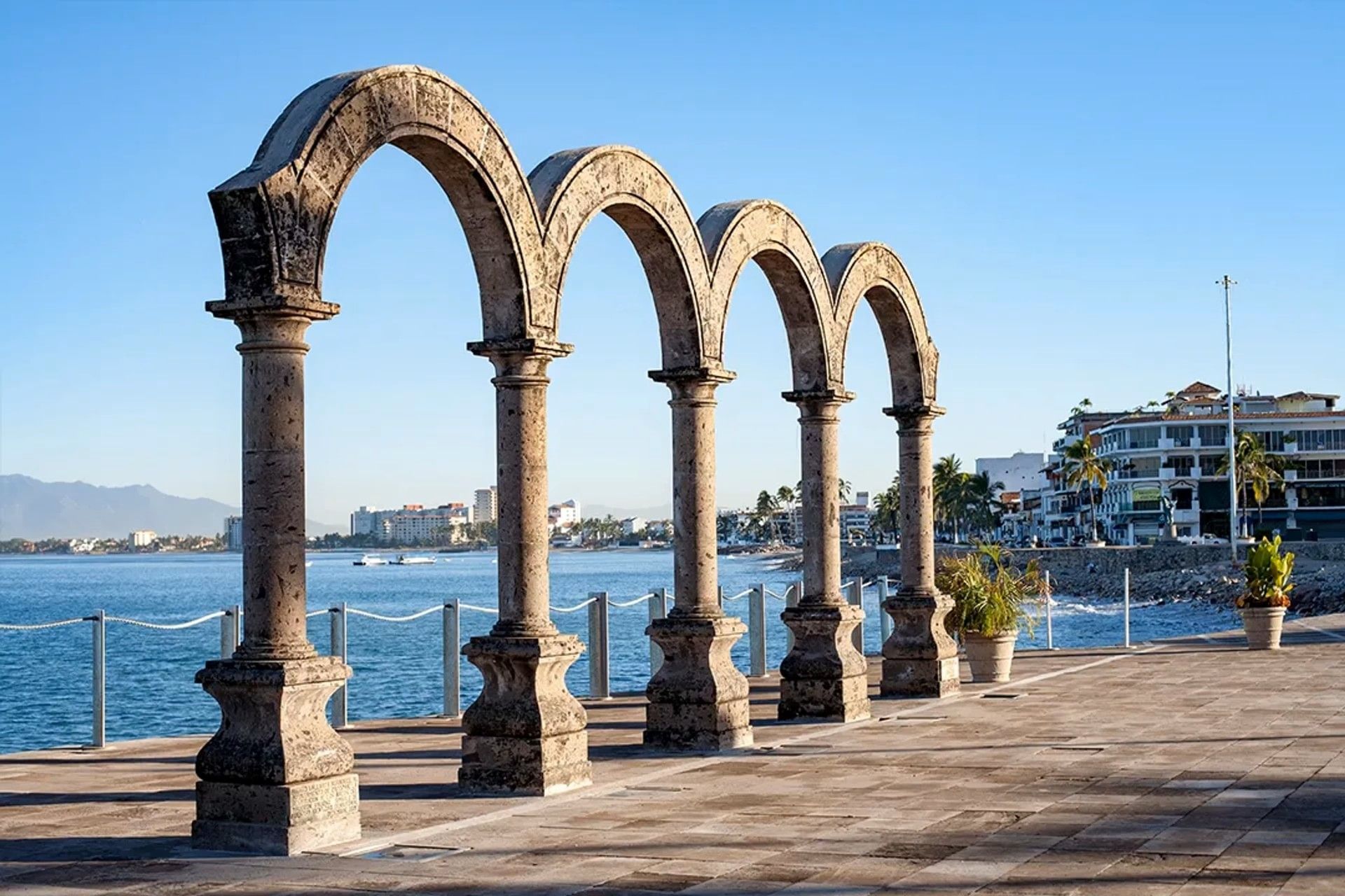 Los Arcos de piedra en el Malecón de Puerto Vallarta frente al mar bajo un cielo azul despejado.