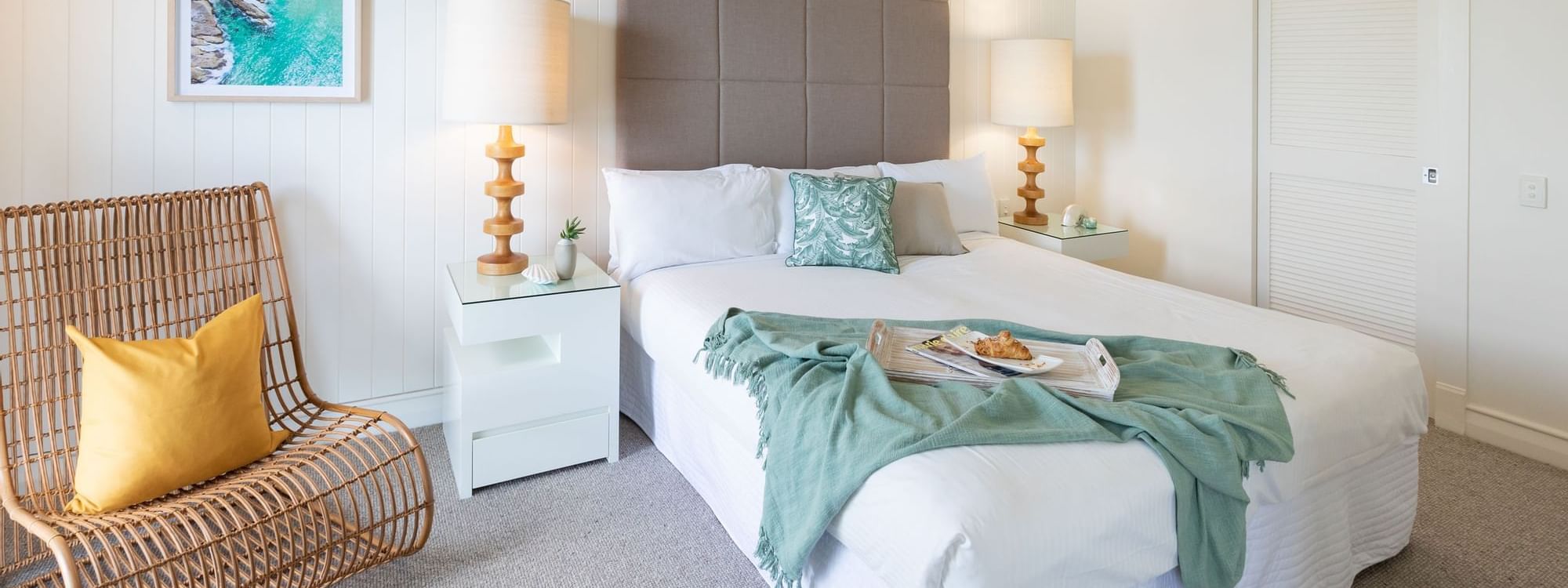 Bed with nightlamps by the couch and carpet floors in the Overwater Bungalow at the Novotel Sunshine Coast Resort