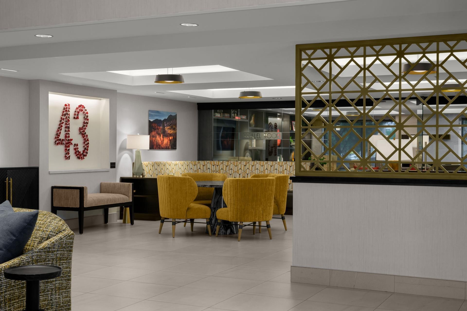 Lobby with a large 43 artwork, yellow velvet chairs, and a decorative screen at Hotel 43 Boise