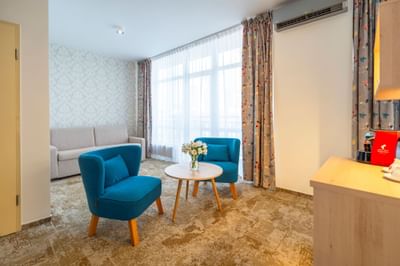 Living area with couch, comfy chairs and round coffee table in Junior Suite at Metropol Hotel
