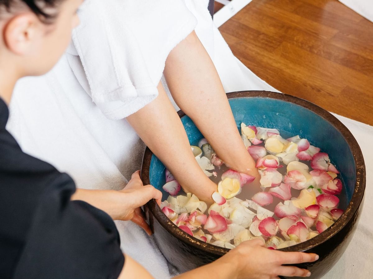 Person soaking feet in a bowl with flower petals at Stephanies Spa, Sofitel Brisbane Central