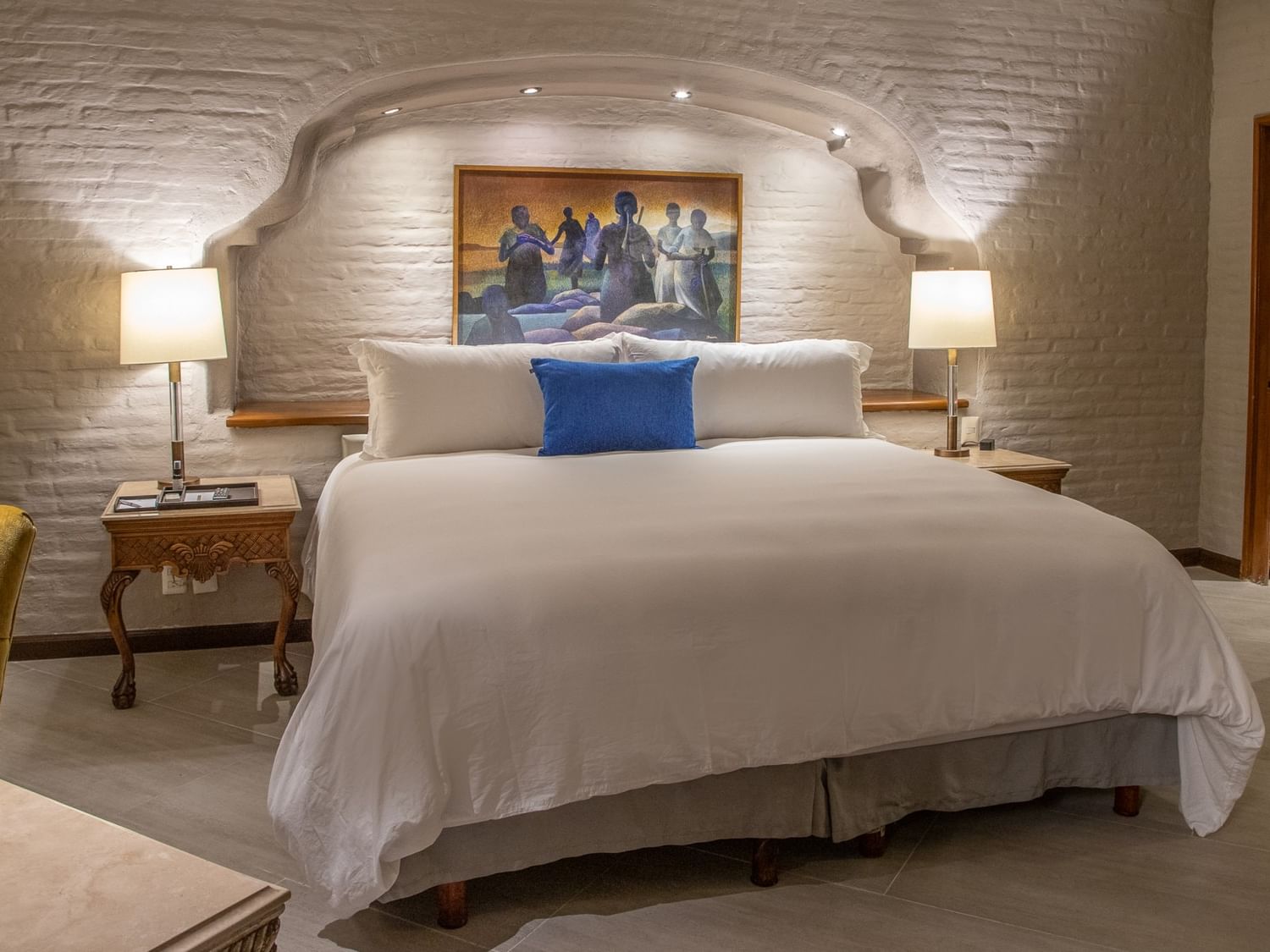 Suite Presidencial King con cama king, pared de ladrillo blanco, arco colonial y lámparas en Quinta Real Guadalajara
