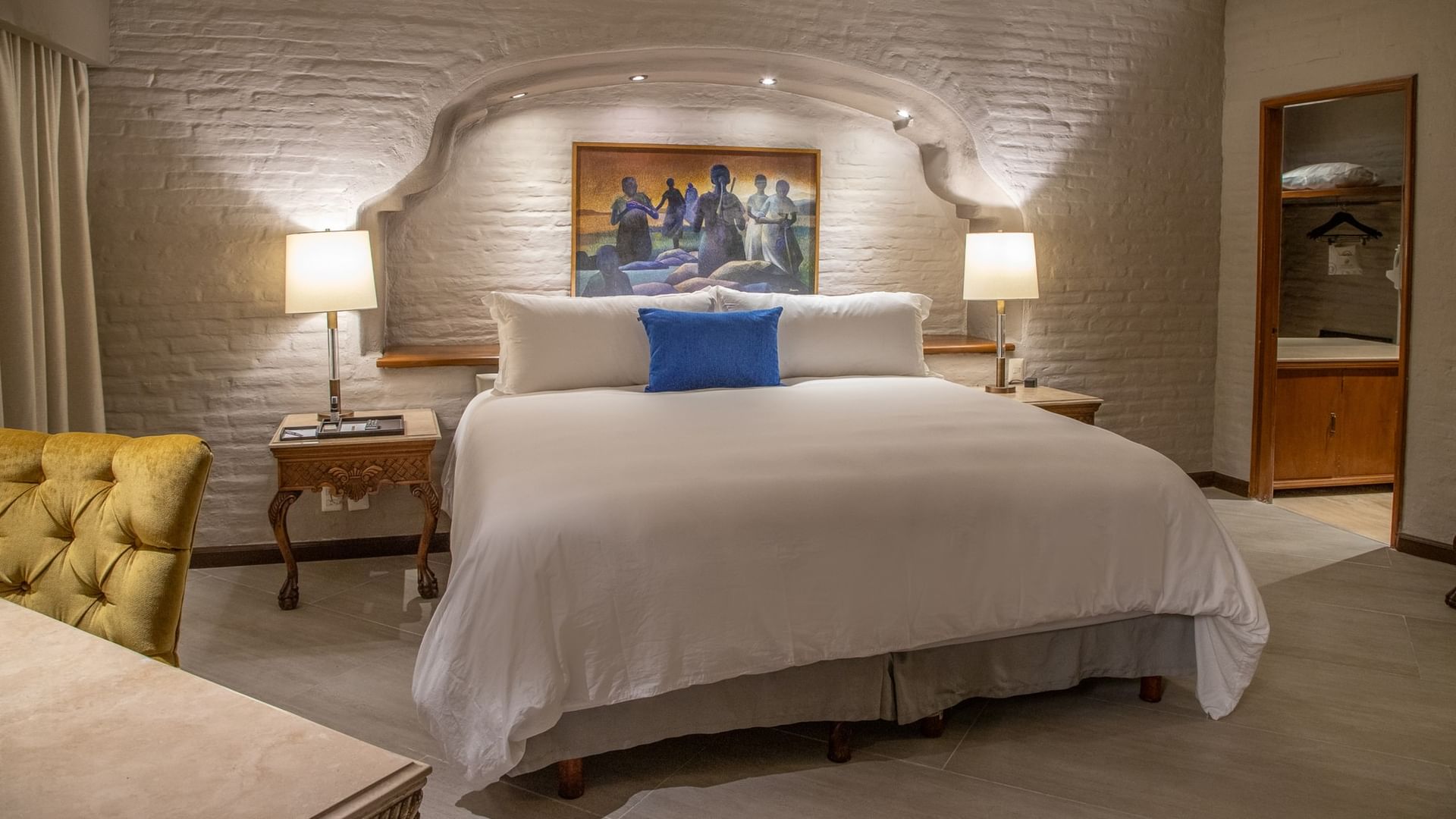 Suite Presidencial King con cama king, pared de ladrillo blanco, arco colonial y lámparas en Quinta Real Guadalajara
