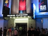 Crowd of people outside Charles Playhouse with Blue Man Group sign lit up in blue.