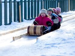Closeup of 3 kids on a toboggan chutes near High Peaks Resort