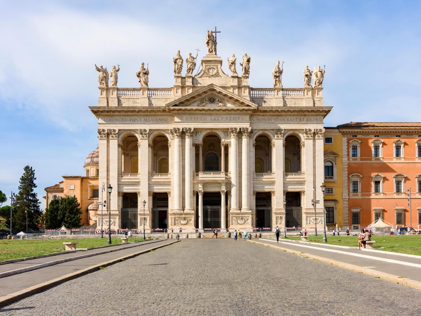 Majestic facade of San Giovanni in Laterano with statues, set against a clear blue sky near The Guardian Hotel