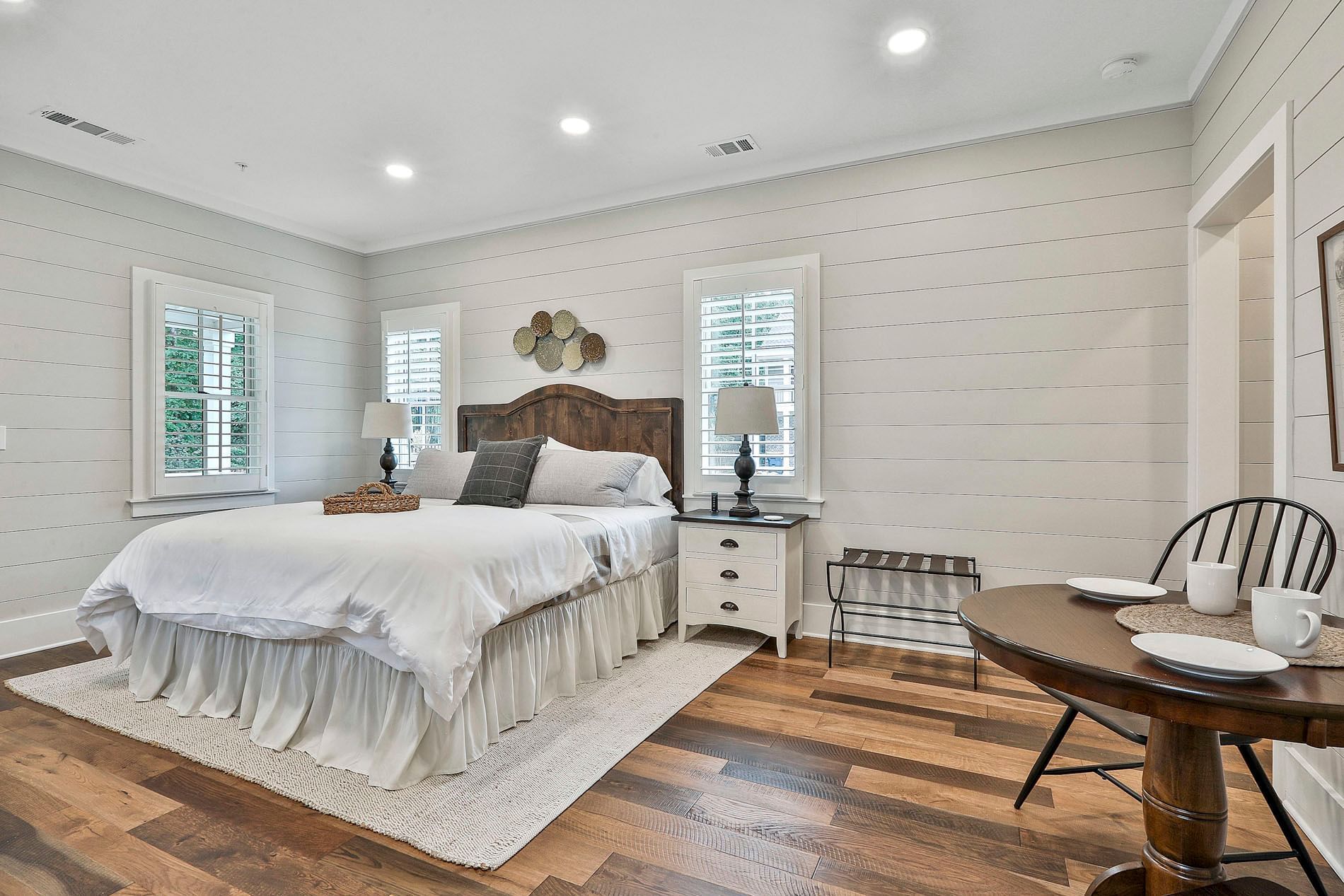 Deluxe King Cottage bedroom with a bed, two lamps, wooden floors, and a mini dining table set by Cottages at Laurel Brooke