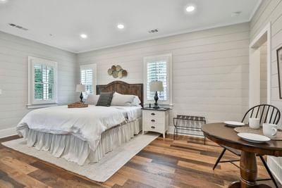 Deluxe King Cottage bedroom with a bed, two lamps, wooden floors, and a mini dining table set by Cottages at Laurel Brooke