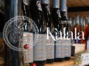 Bottles of Kalala Organic Estate Winery wine lined up on a shelf.