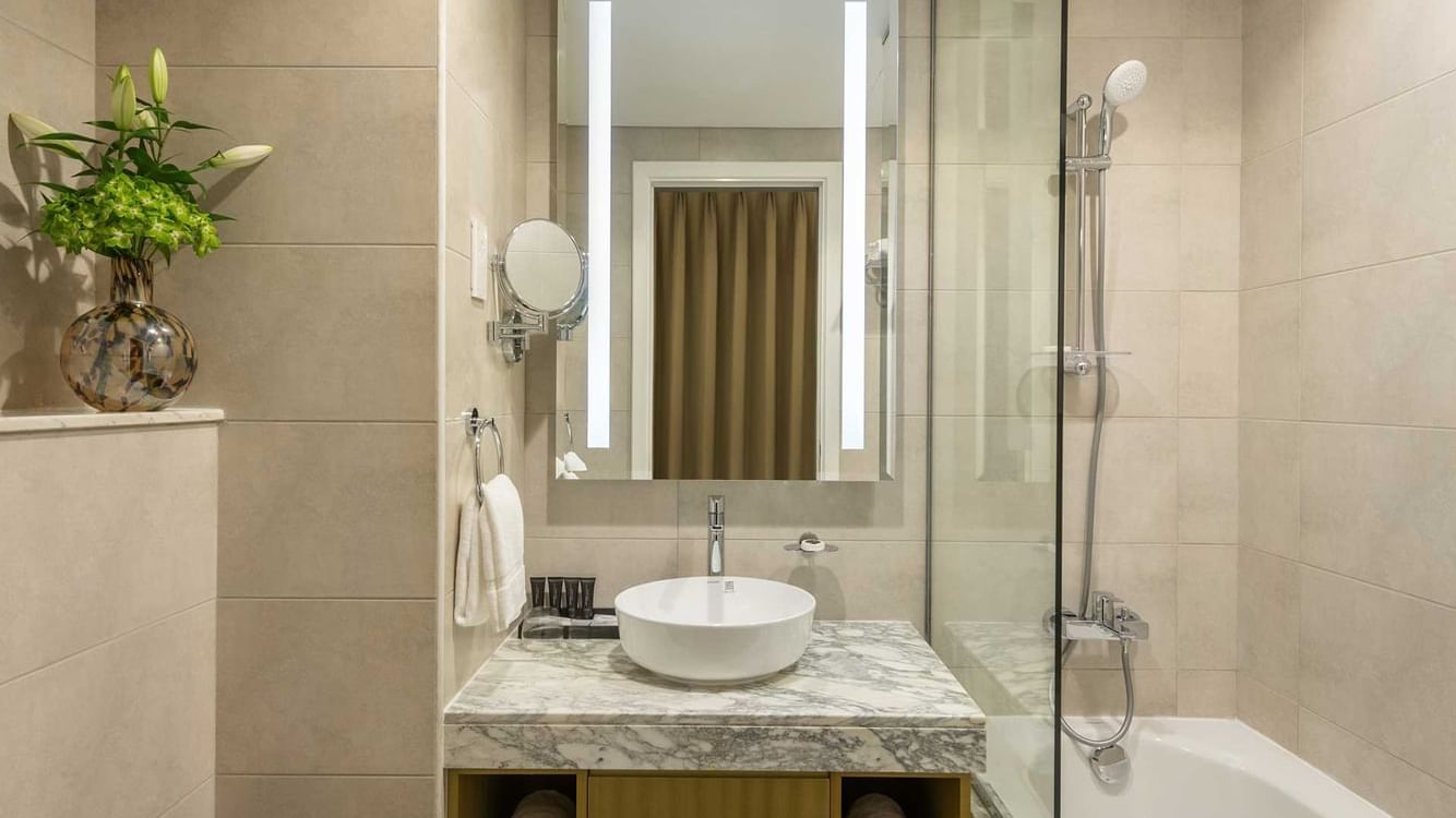 Bathroom shower by the marbled vanity in Studio Apartments at DAMAC Maison Aykon City